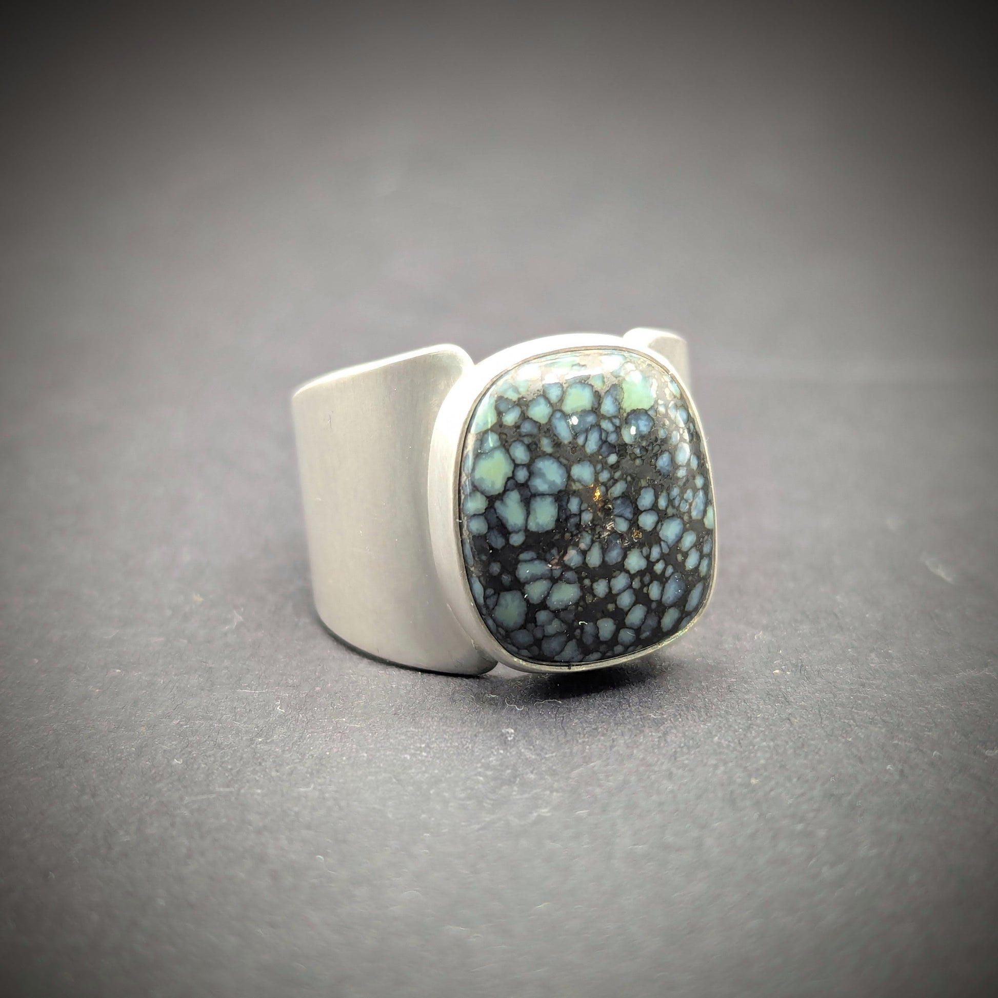 Silver ring with a textured blue stone on a gray background