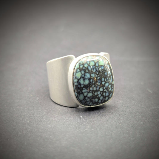 Silver ring with a textured blue stone on a gray background